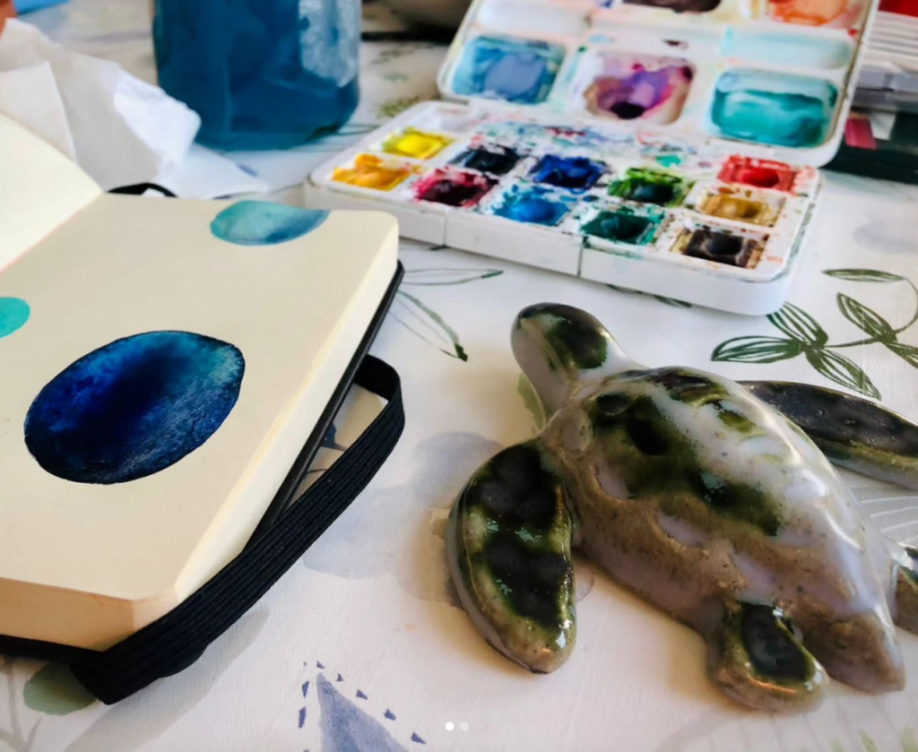 Ceramic turtle on a desk with watercolour paints