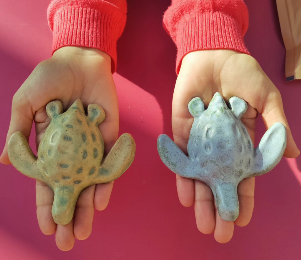 Two ceramic turtles being held in hands