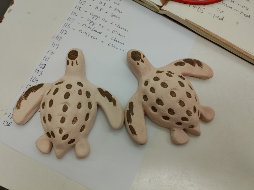 Two ceramic turtles against a background of paper